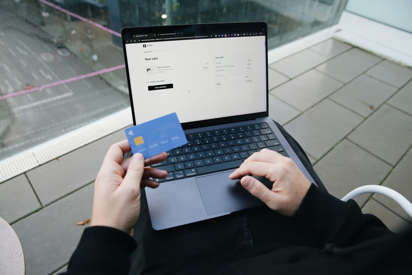 Hände tippen am Laptop, daneben eine Bezahlkarte